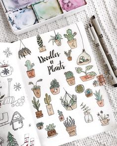 an open notebook with doodles of plants on it and some pens next to it