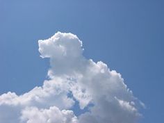 the airplane is flying high in the blue sky with white fluffy clouds behind it,