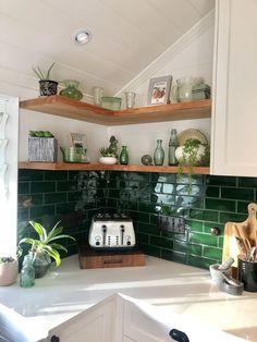 a kitchen with green tiles and wooden shelves