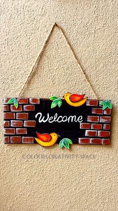 a welcome sign hanging from the side of a brick wall with fruit painted on it