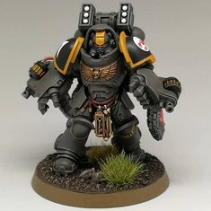 a grey and yellow painted warhammer is standing on the ground