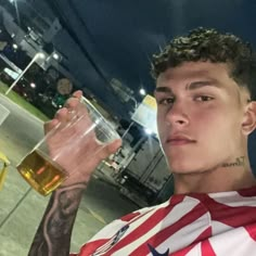 a man with tattoos holding a glass of beer