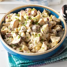 a blue bowl filled with potato salad on top of a table