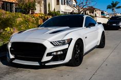 a white mustang parked in front of a house