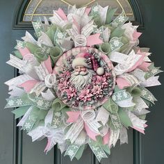 a wreath with a santa clause on it hanging from the side of a green door