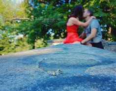 a man and woman kissing on top of a rock