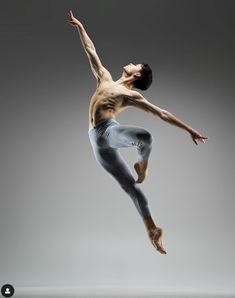 a male ballet dancer in the air with his arms outstretched and legs spread out to the side