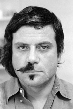 a black and white photo of a man with a moustache on his face