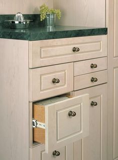 a kitchen with white cabinets and green marble counter tops on the top shelf is an open drawer