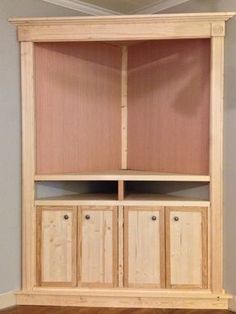 a wooden bookcase with two doors and three cupboards on the bottom, in front of a gray wall