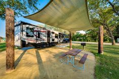 an rv park with picnic tables and benches under a shade sail on the side of the road