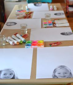 the table is set up with several pictures on paper and markers, pencils, watercolor pens and other items