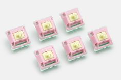 six pink plastic plugs with yellow light inside them on a white surface, top view