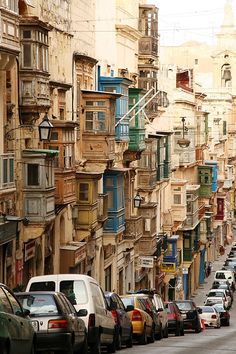 many cars are parked on the street in front of tall buildings and balconies