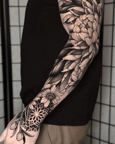 a person with a black and white tattoo on their arm, holding onto a flower