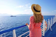 a woman in a red and white striped dress looking out at the ocean from a cruise ship