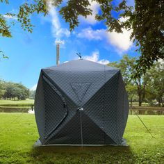 a large black umbrella sitting on top of a lush green field