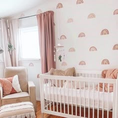 a baby's room with a white crib, pink curtains and a brown chair