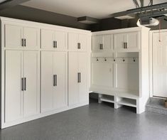 an empty garage with white cabinets and gray flooring