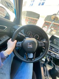 a person driving a car on the street with their hands on the steering wheel and dashboard