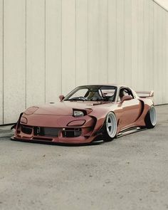 a pink sports car parked in front of a white wall