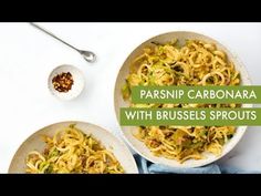 two white bowls filled with pasta and topped with parmesan sprouts next to a spoon