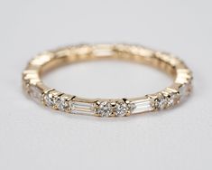 a yellow gold ring with five baguettes and three diamonds on the side, sitting on a white surface