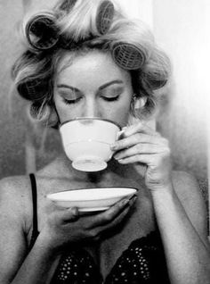 a black and white photo of a woman drinking from a cup