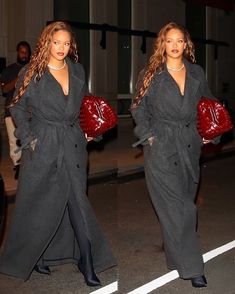 two women are walking down the street in long coats and holding red purses,