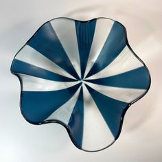 a blue and white striped glass dish on a white tableclothed surface, with the center piece in the shape of a flower