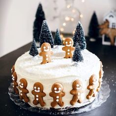 a frosted cake decorated with gingerbread men and trees on a black countertop