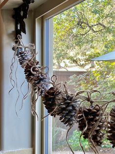 some pine cones are hanging from a window sill