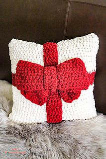 a crocheted pillow with a red bow on it