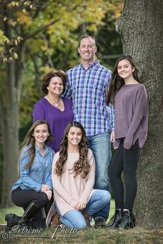 a family poses in front of a tree