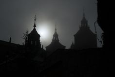 the sun shines through the foggy sky over rooftops in an urban area