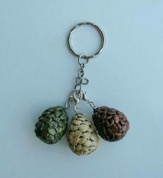 three different types of acorns hanging from a keychain on a white surface