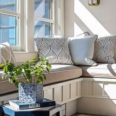 a window seat with pillows and a potted plant