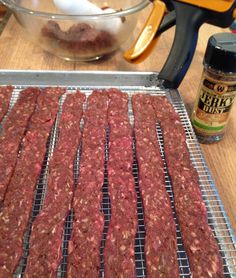 raw ground meat is being cooked on a grill in front of a glass bowl with seasoning