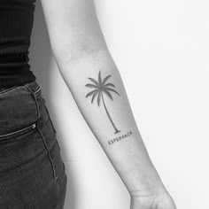 a woman's arm with a small palm tree tattoo on the left inner forearm