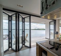 an open kitchen and dining area with sliding glass doors leading to the deck overlooking water