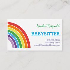 a babysitter business card with a rainbow in the middle on a marble surface