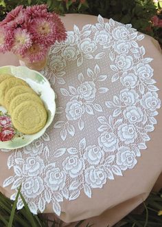 a white doily on a table with pink flowers