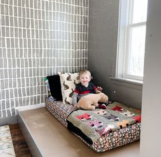 a little boy sitting on top of a couch with a stuffed animal in front of him