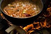 a pot filled with food sitting on top of a fire