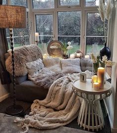 a living room filled with lots of furniture next to a large window covered in blankets