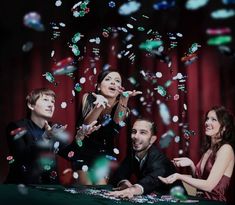 a group of people standing around a table with confetti falling from the air