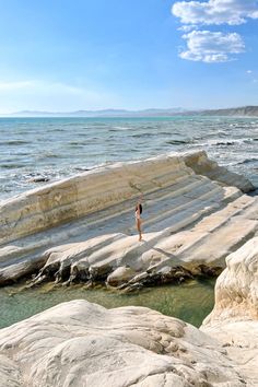 a person standing on some rocks near the ocean