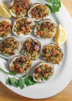 a white plate topped with oysters covered in sauce and garnished with parsley