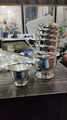 two silver bowls sitting on top of a wooden table