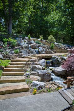 there are many steps that lead up to the waterfall in this backyard garden with rocks and flowers